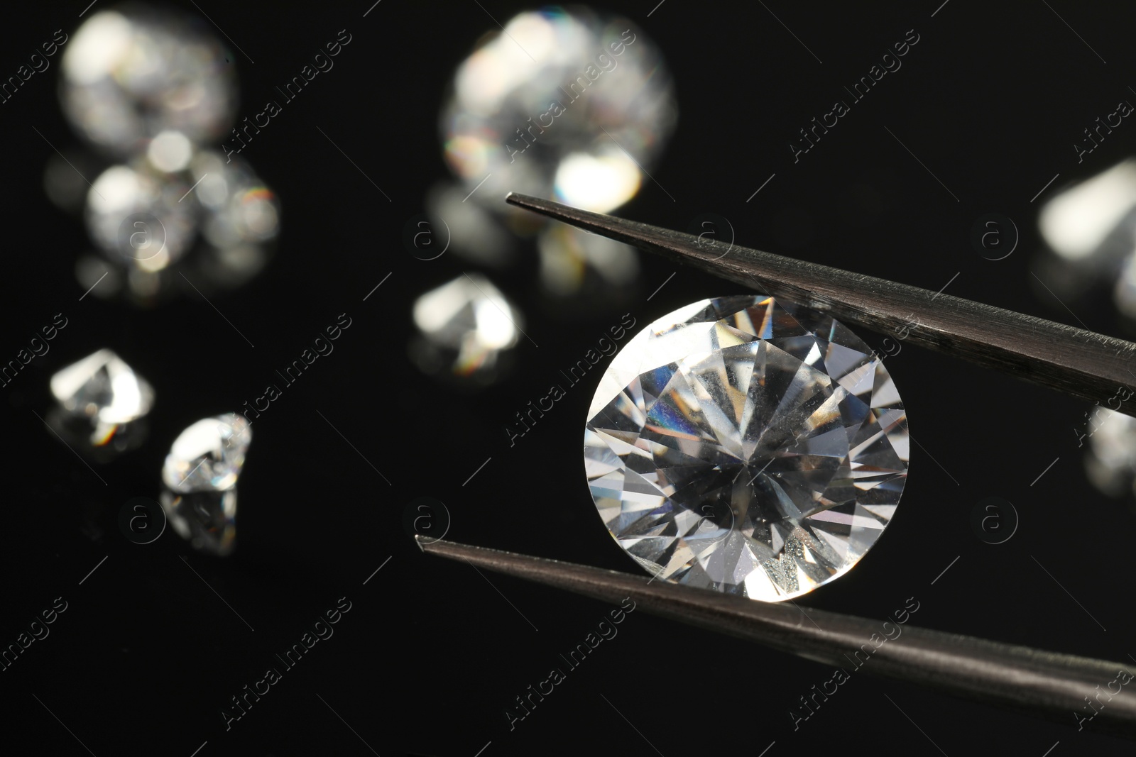 Photo of Tweezers with beautiful shiny diamonds on black background, closeup