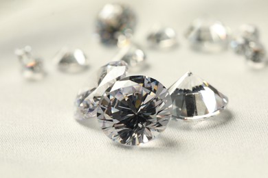 Many beautiful shiny diamonds on white fabric, closeup