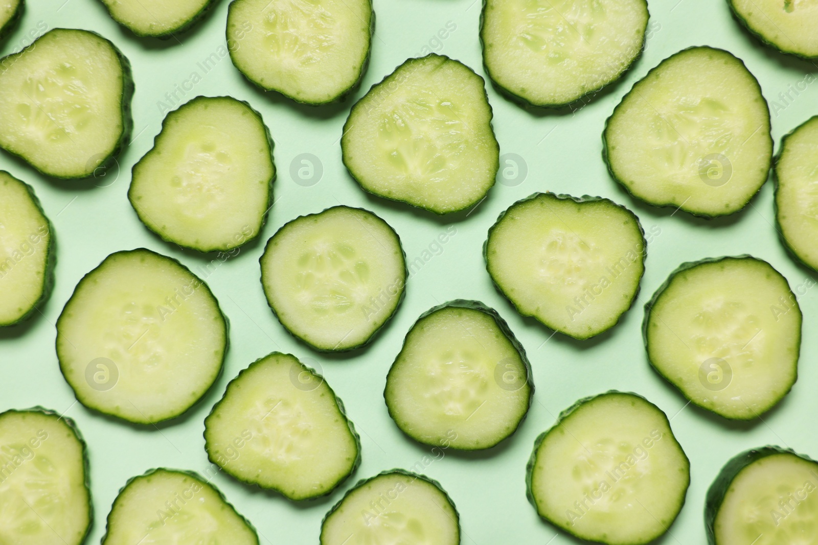 Photo of Slices of fresh cucumbers on turquoise background, flat lay