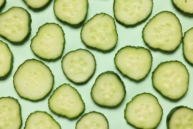 Photo of Slices of fresh cucumbers on turquoise background, flat lay