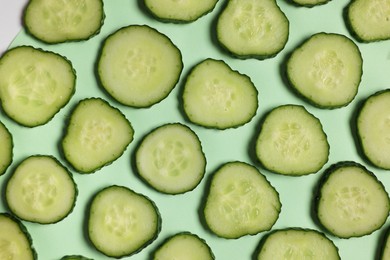 Photo of Slices of fresh cucumbers on turquoise background, flat lay