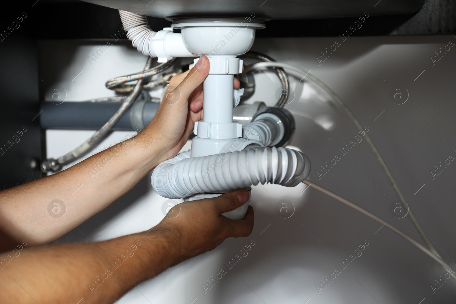 Photo of Professional plumber fixing piping system at home