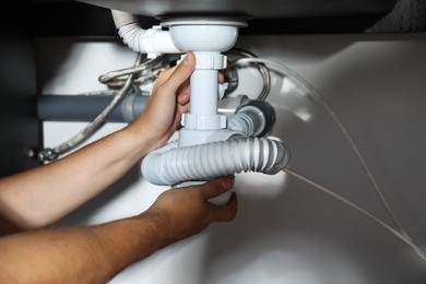 Photo of Professional plumber fixing piping system at home