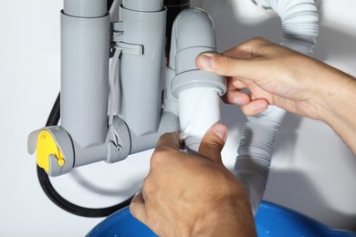 Photo of Professional plumber fixing piping system at home, closeup