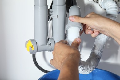 Photo of Professional plumber fixing piping system at home, closeup