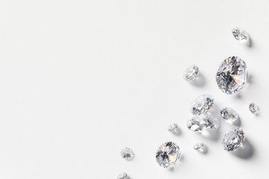 Photo of Many beautiful shiny diamonds on white background, flat lay. Space for text