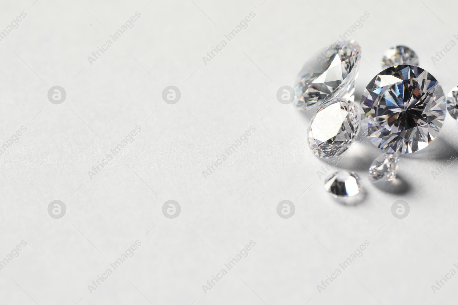 Photo of Many beautiful shiny diamonds on white background. Space for text