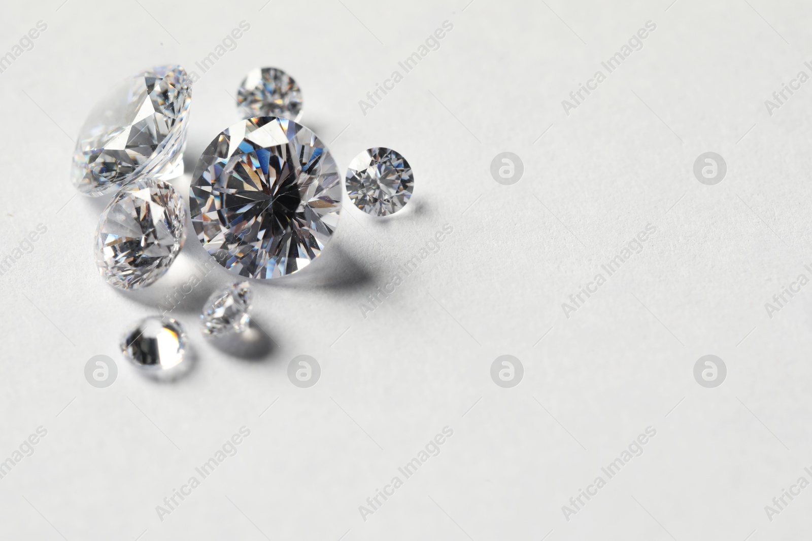 Photo of Many beautiful shiny diamonds on white background. Space for text