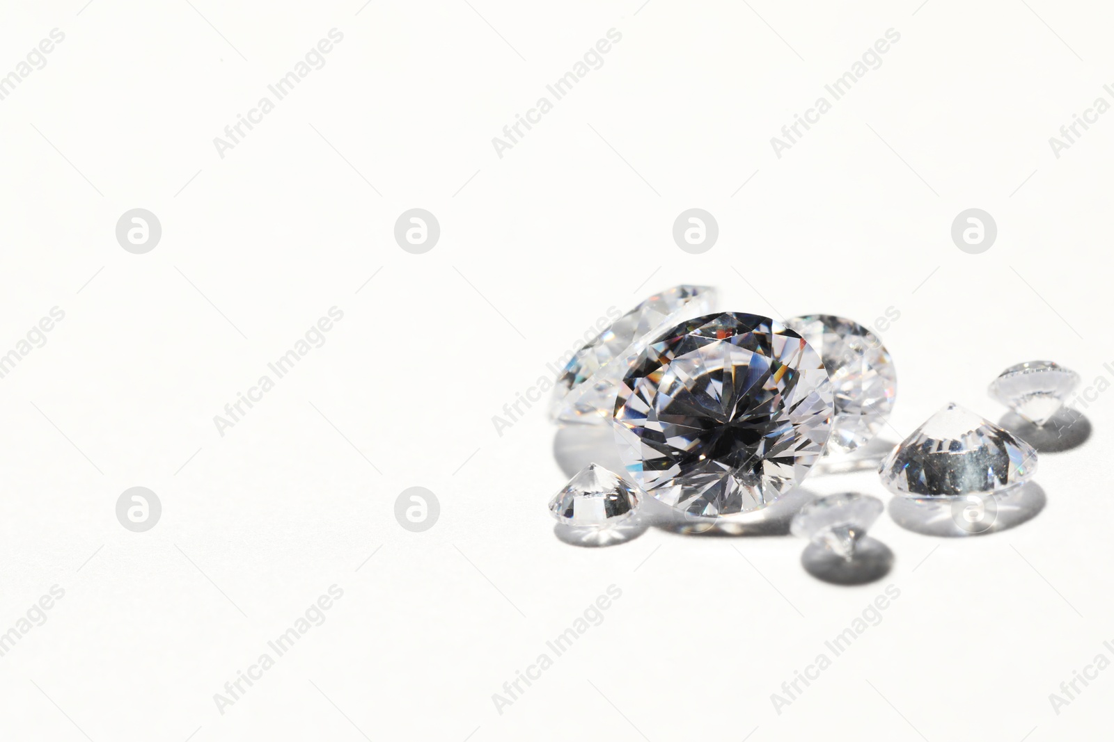 Photo of Many beautiful shiny diamonds on white background, closeup. Space for text