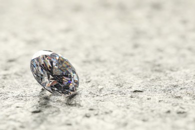 Photo of Beautiful shiny diamond on grey textured table, closeup. Space for text