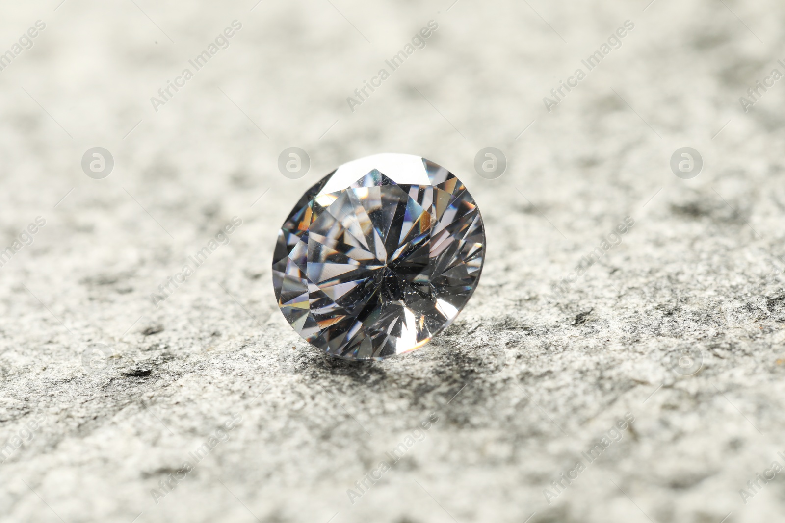 Photo of Beautiful shiny diamond on grey textured table, closeup