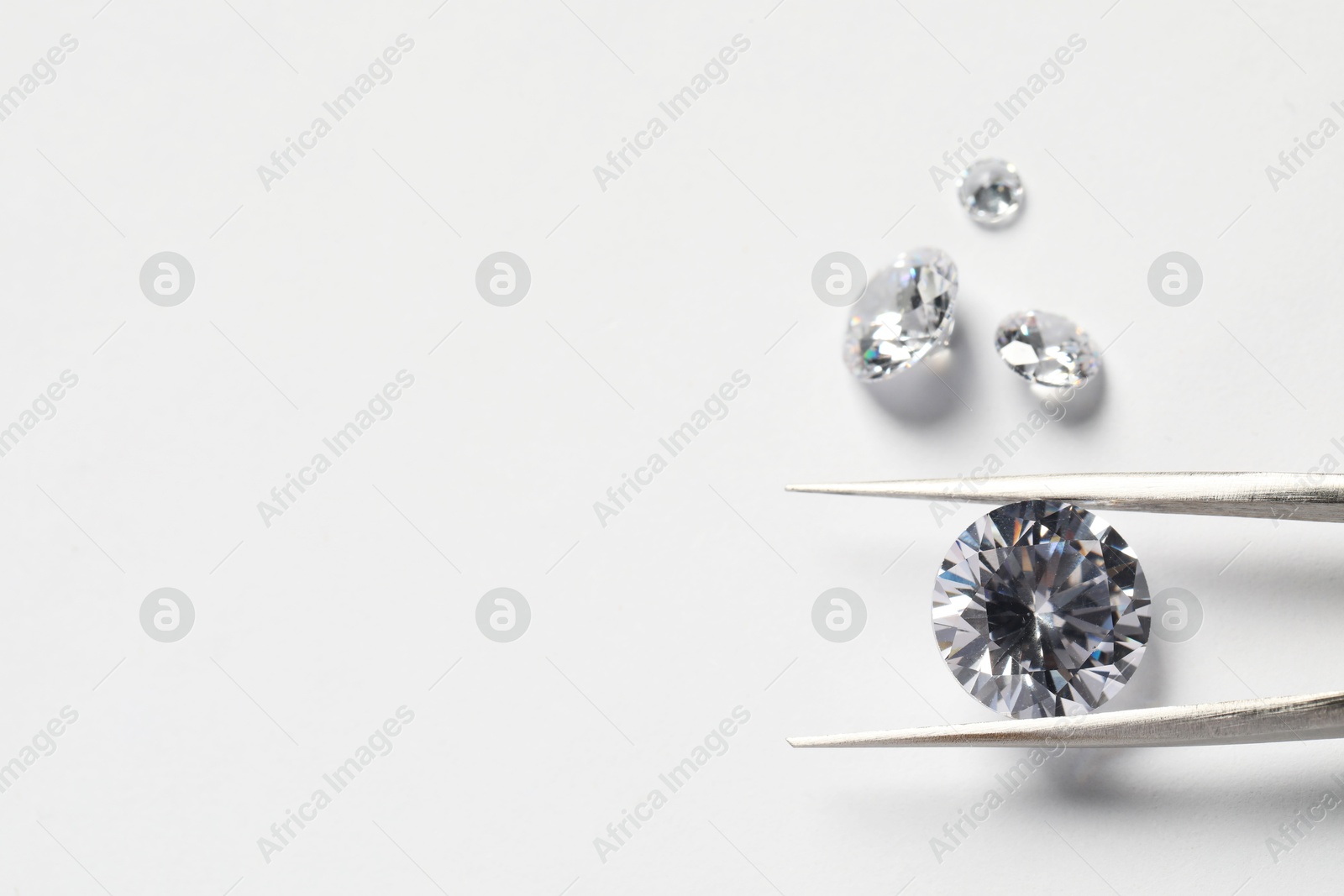 Photo of Many beautiful shiny diamonds and tweezers on white background. Space for text