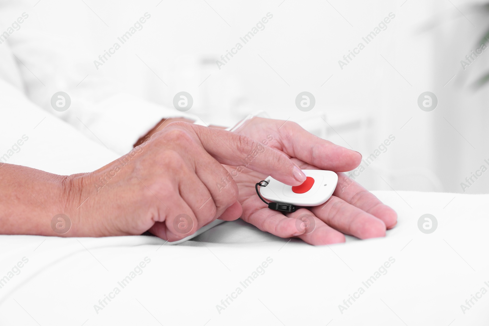 Photo of Senior woman pressing emergency call button on bed in hospital, closeup