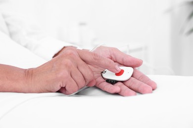 Photo of Senior woman pressing emergency call button on bed in hospital, closeup