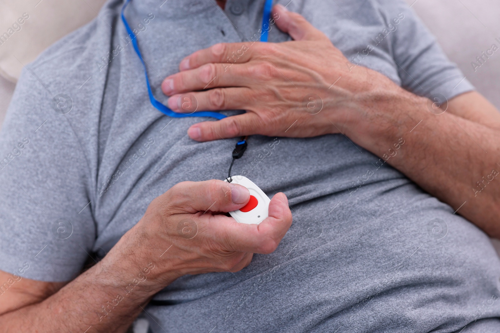 Photo of Senior man pressing emergency call button at home, closeup