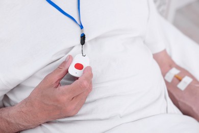 Photo of Senior man with emergency call button on bed in hospital, closeup