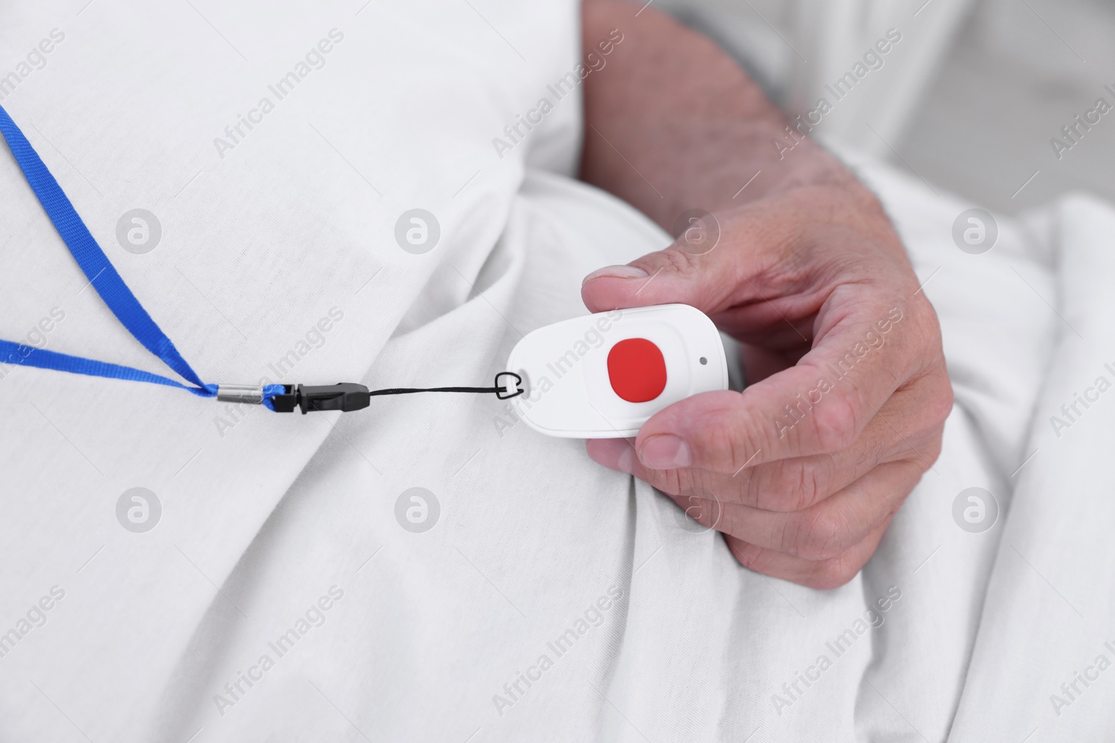 Photo of Senior man with emergency call button on bed in hospital, closeup