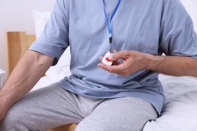 Senior man pressing emergency call button on bed in hospital, closeup