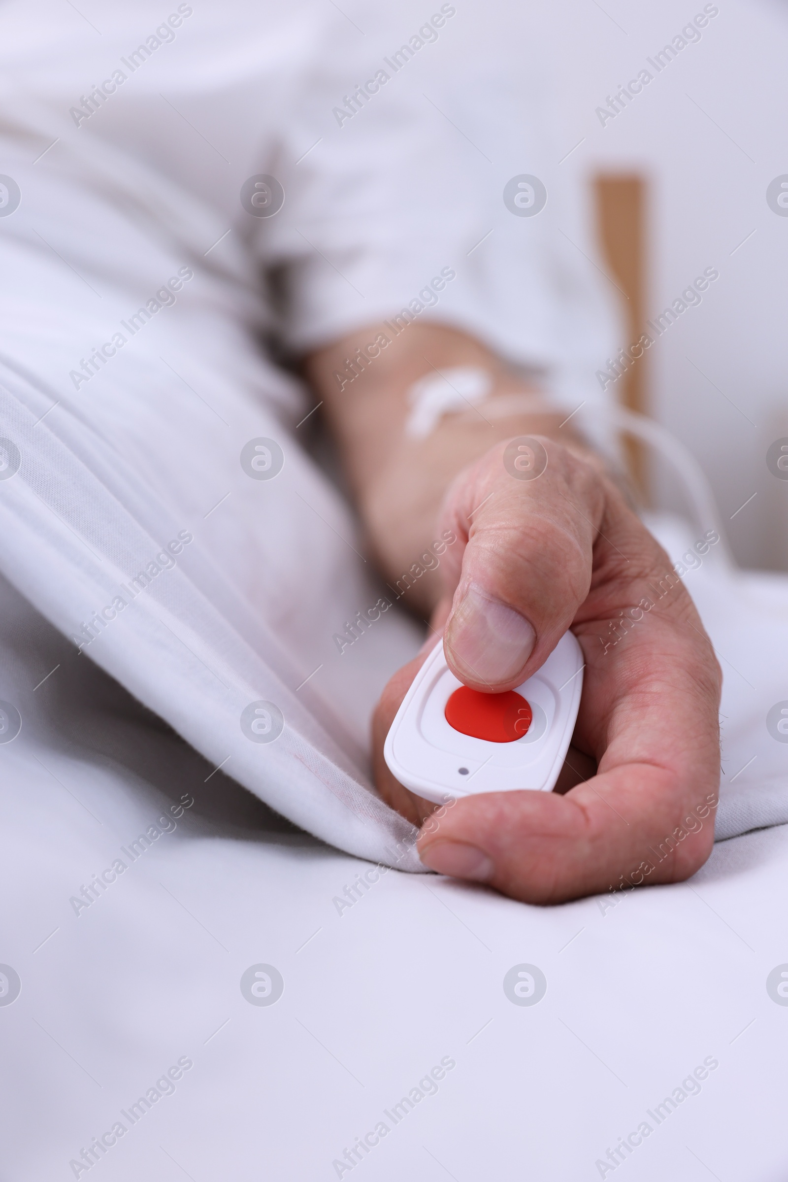 Photo of Senior man with emergency call button on bed in hospital, closeup