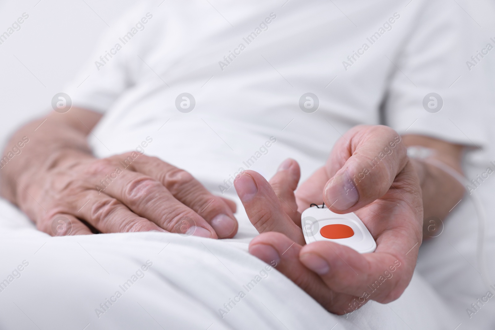 Photo of Senior man with emergency call button on bed in hospital, closeup