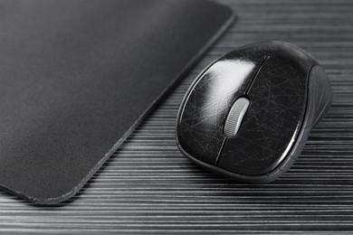 Photo of Computer mouse with mousepad on black wooden table, closeup