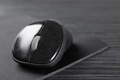 Photo of Computer mouse with mousepad on black wooden table, closeup