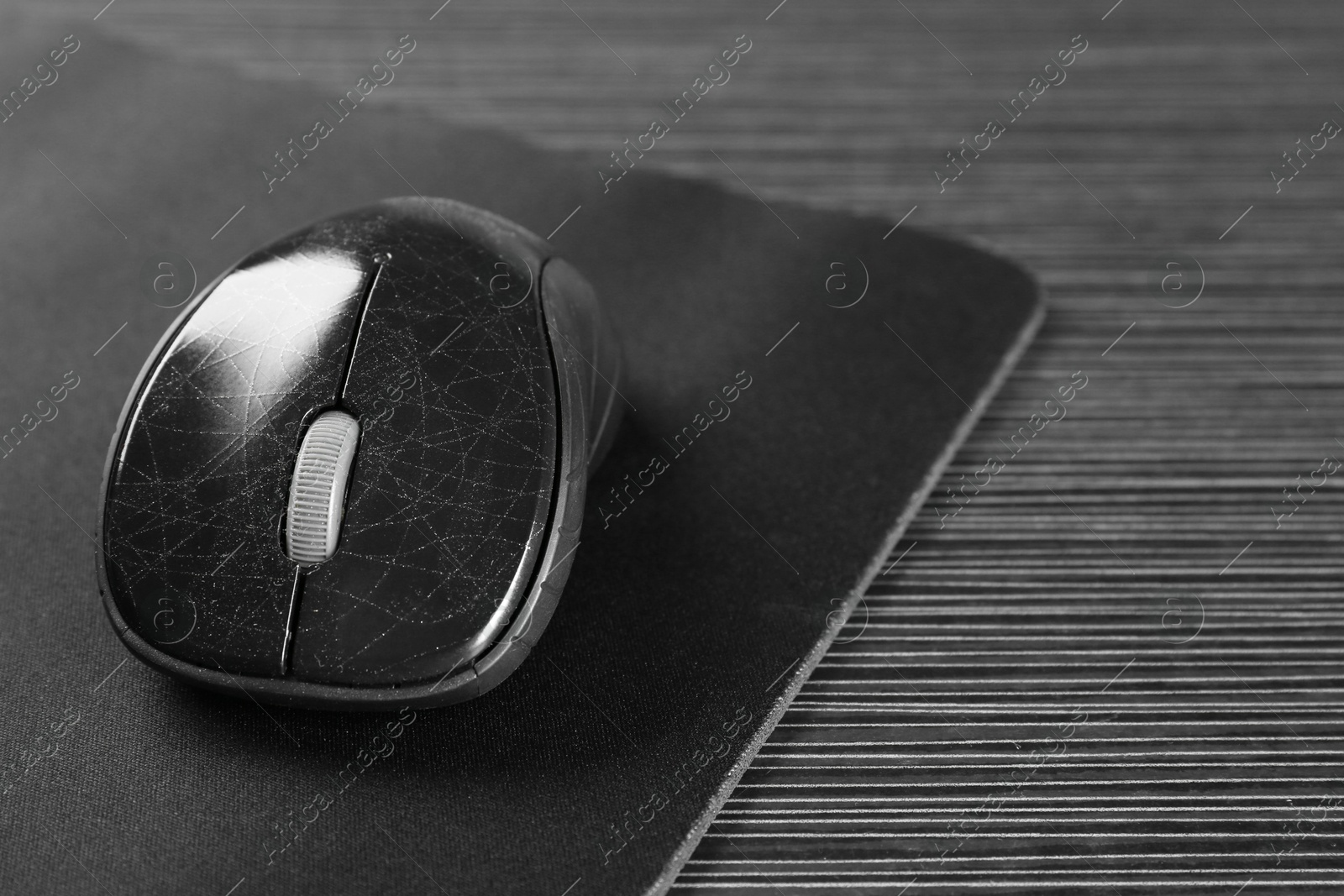 Photo of Computer mouse with mousepad on black wooden table, closeup. Space for text