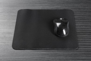 Photo of Computer mouse with mousepad on black wooden table