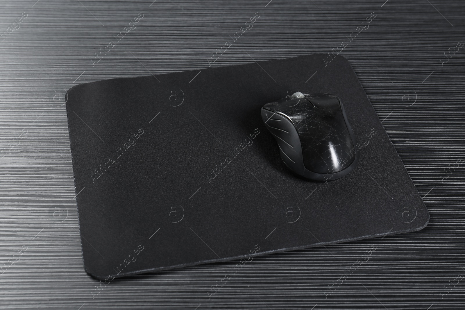 Photo of Computer mouse with mousepad on black wooden table