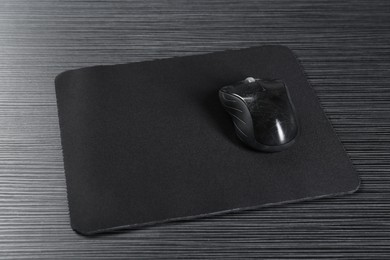 Photo of Computer mouse with mousepad on black wooden table