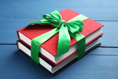 Books tied with green ribbon as gift on blue wooden table