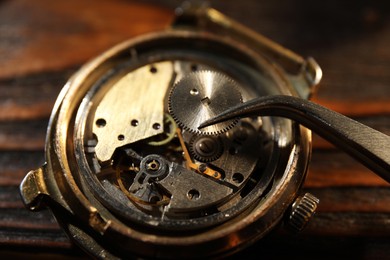 Mechanism of vintage wrist watch and tool on table, closeup