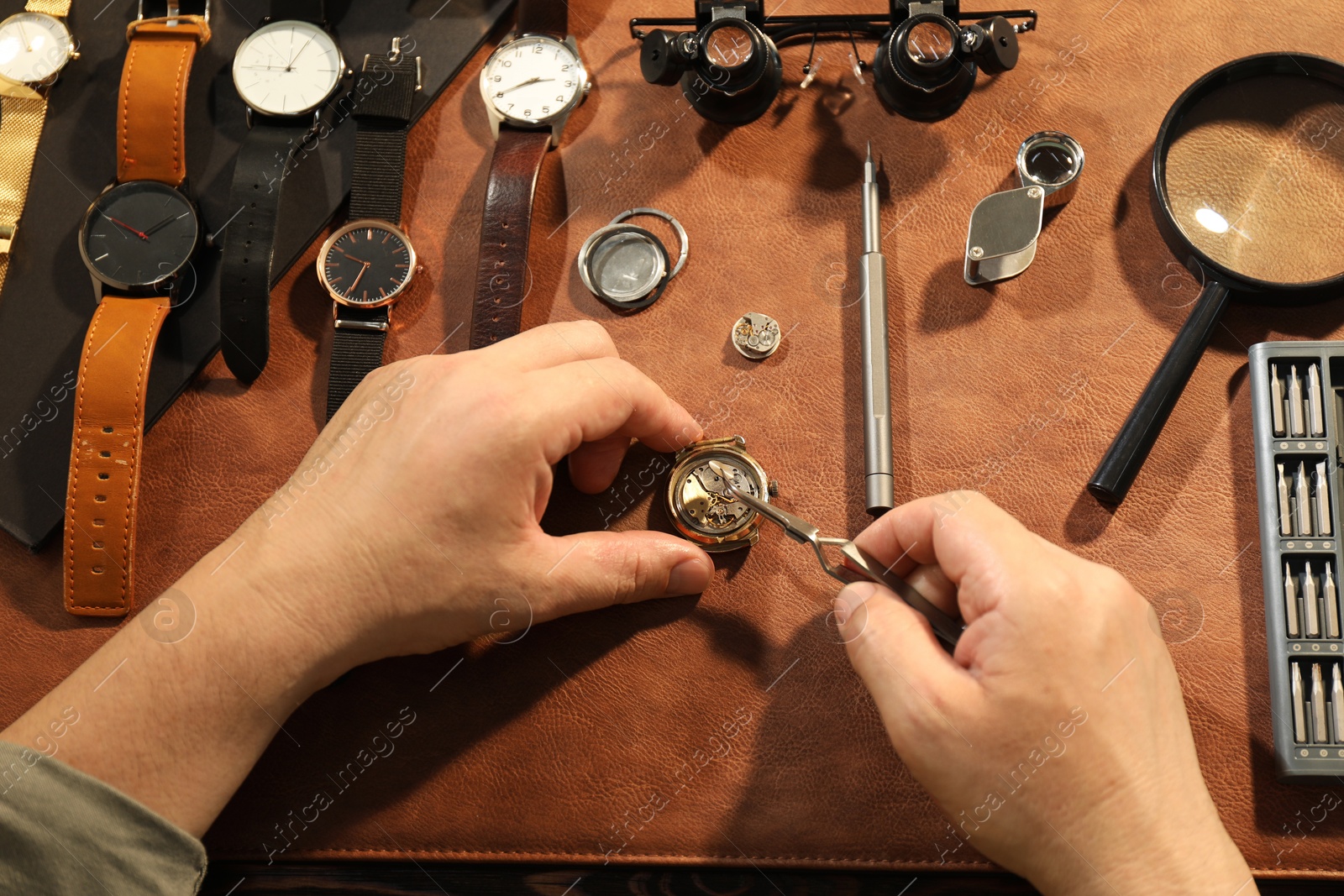 Photo of Man fixing mechanism of vintage wrist watch at table, top view