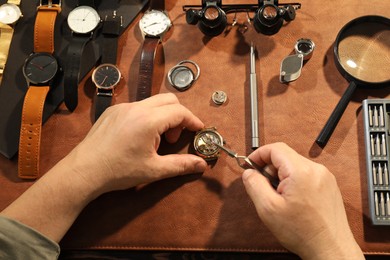 Photo of Man fixing mechanism of vintage wrist watch at table, top view