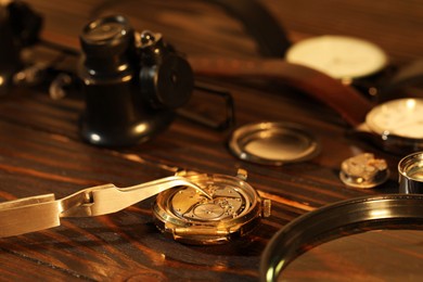 Photo of Mechanism of vintage wrist watch and tool on wooden table, closeup