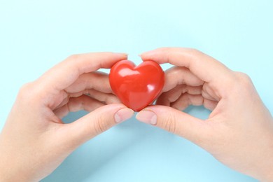 Photo of Woman with red heart on light blue background, closeup