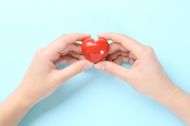 Photo of Woman with red heart on light blue background, closeup