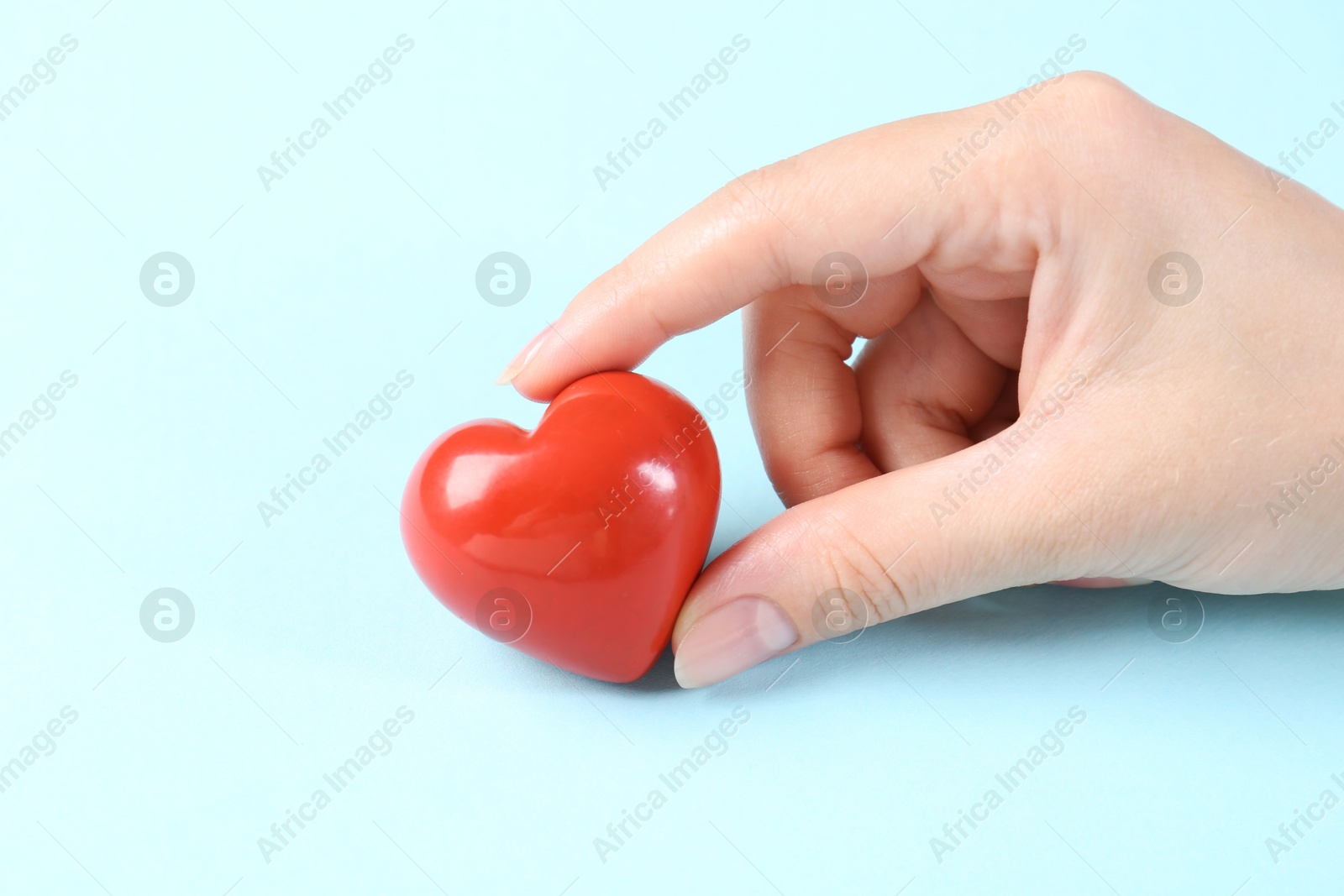 Photo of Woman with red heart on light blue background, closeup