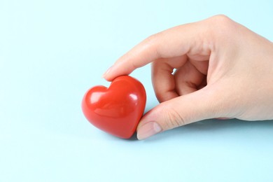 Photo of Woman with red heart on light blue background, closeup