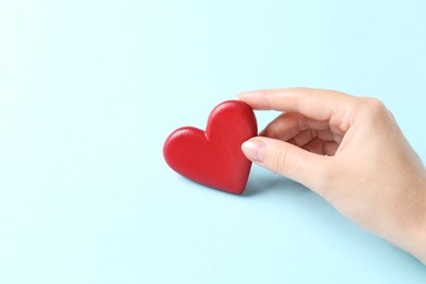 Photo of Woman with red heart on light blue background, closeup