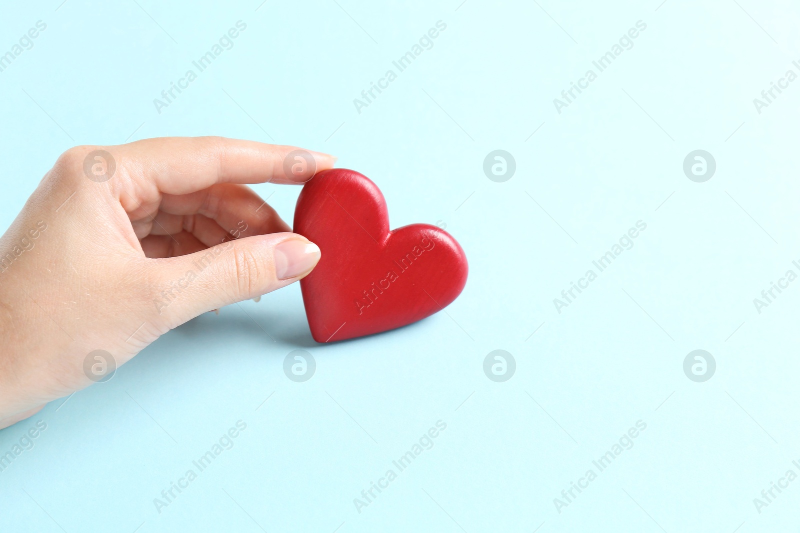 Photo of Woman with red heart on light blue background, closeup