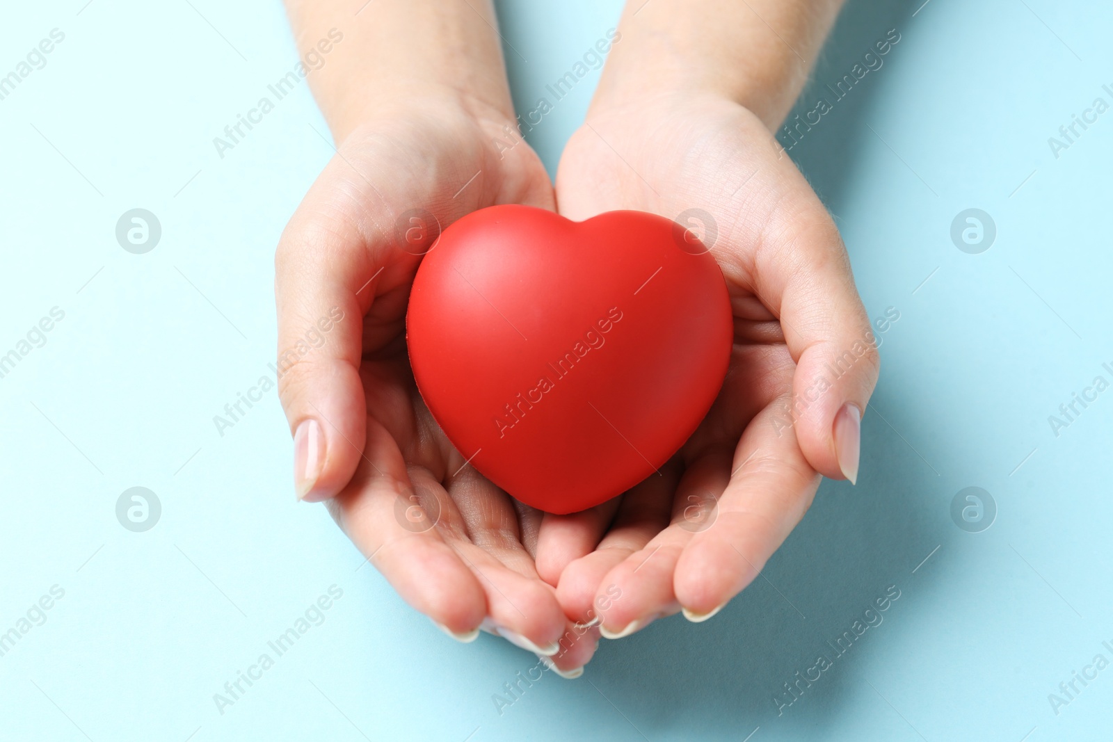 Photo of Woman with red heart on light blue background, closeup