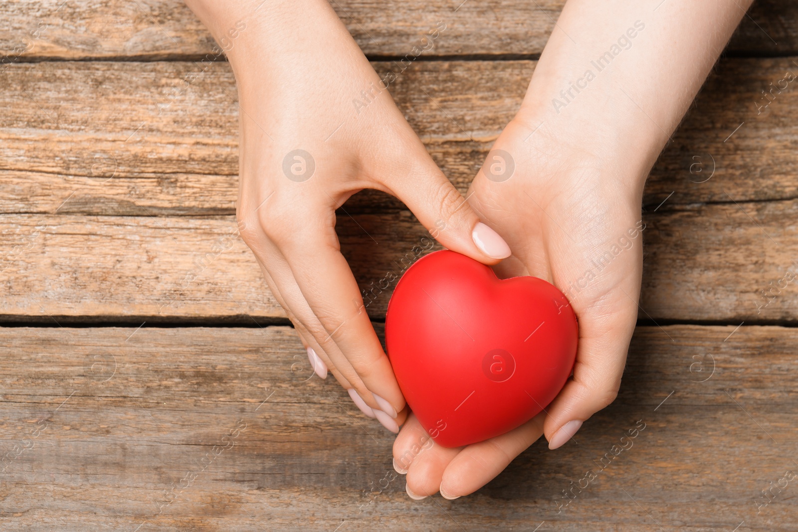 Photo of Woman with red decorative heart at wooden table, top view