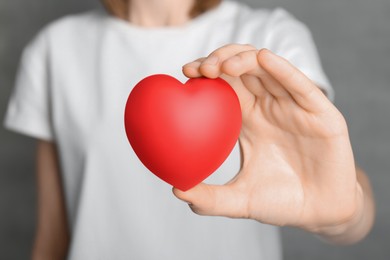 Photo of Woman holding red heart on grey background, closeup