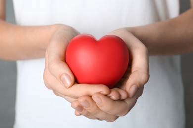 Photo of Woman holding red heart on grey background, closeup