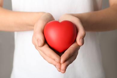 Photo of Woman holding red heart on grey background, closeup