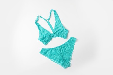 Photo of Elegant turquoise lace women's underwear on white background, top view