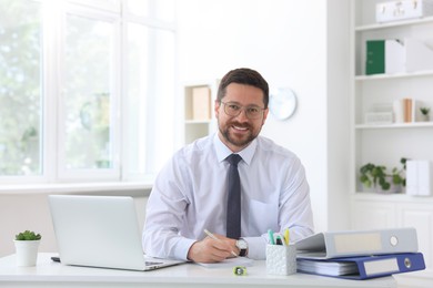 Photo of Portrait of smiling businessman at table in office