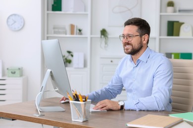 Photo of Smiling businessman working at table in office