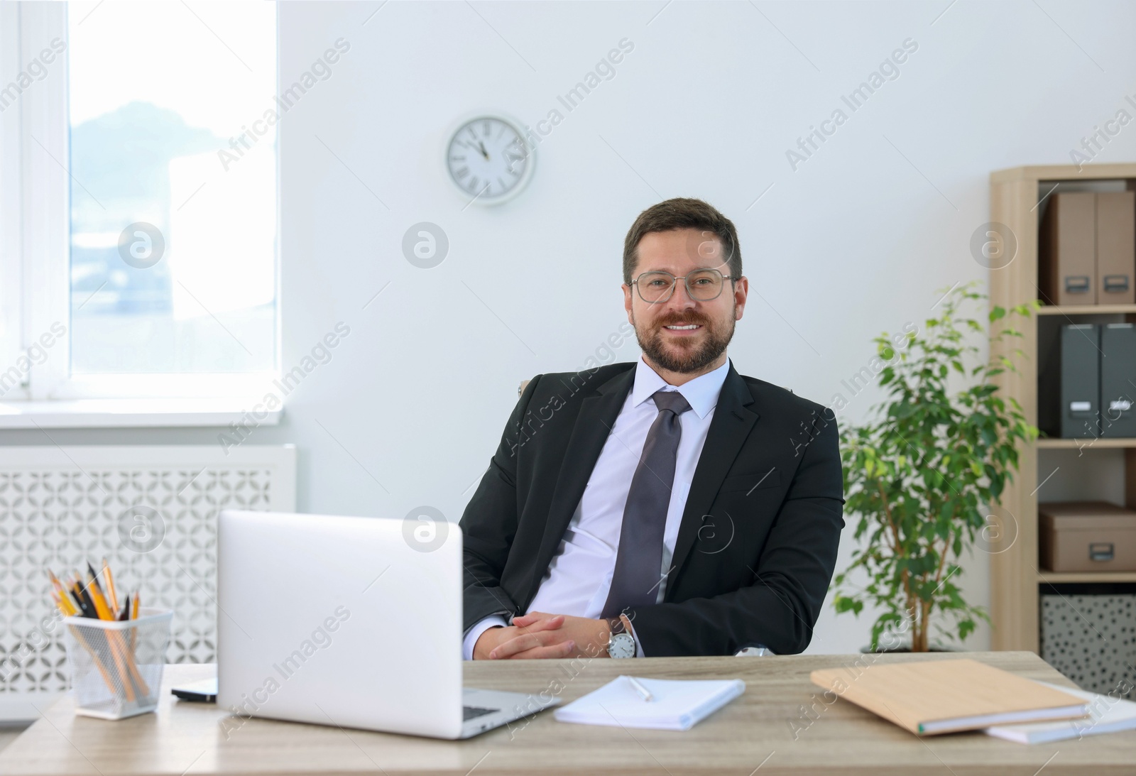 Photo of Portrait of smiling businessman at table in office